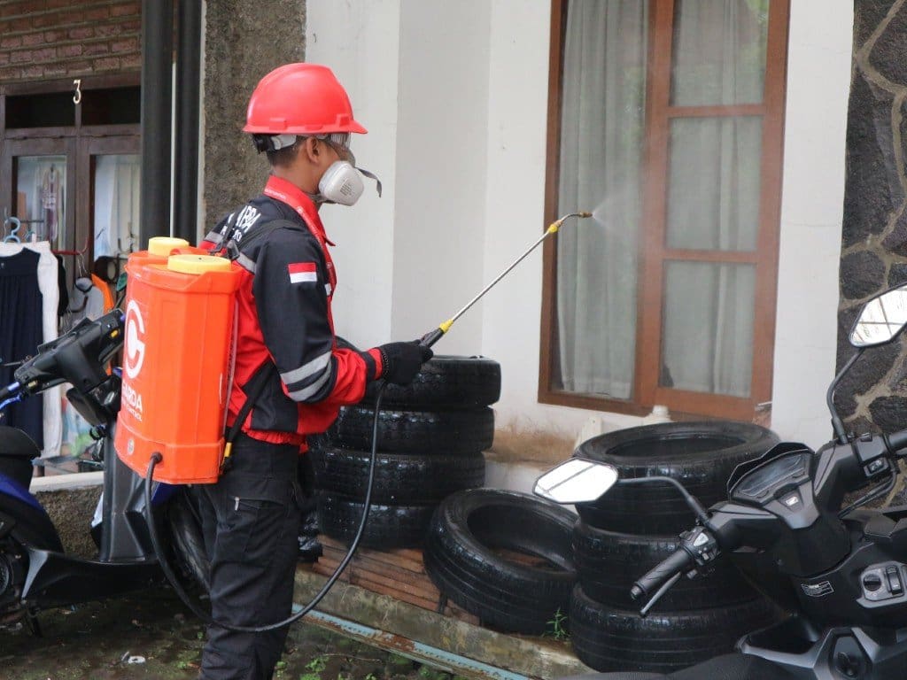 Pest control professional spraying around a residential property for pest control services near me